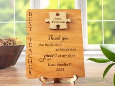 a wooden puzzle piece with the words best teacher on it and a flower pot in the background