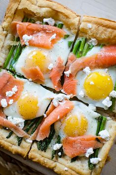 an egg and asparagus pizza is shown on a white plate with other food items