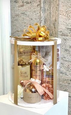 an open gift box on top of a white table with gold ribbon and bow around it