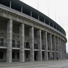 a large building with many columns on the outside and people walking in front of it