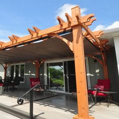 a wooden pergolan sitting on top of a wooden deck next to a building