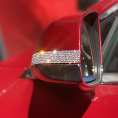 the side view mirror of a red car with some diamonds on it's sides