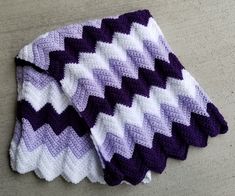 a purple and white crocheted blanket sitting on top of a table