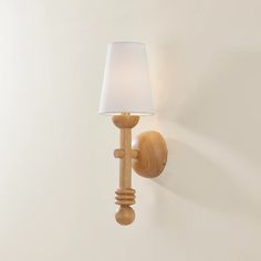 a wooden wall light with a white shade on it's side and a lamp attached to the wall