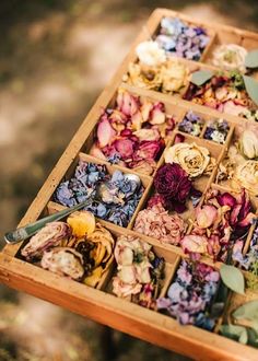 a wooden box filled with lots of different types of flowers and leaves on top of it