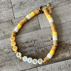 a yellow and white beaded bracelet with words on it that spell out kind of love