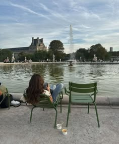 two people sitting on lawn chairs in front of a fountain