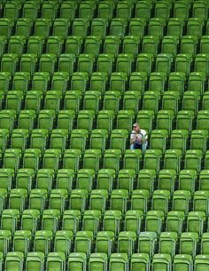 a man sitting in the middle of a large stadium filled with green chairs