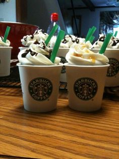 starbucks coffee cups with green straws and whipped cream on the top are lined up