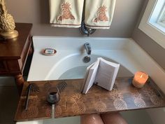 a person is sitting in front of a bathtub with towels on it and a candle