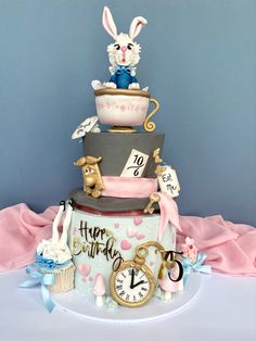 a three tiered cake decorated with cupcakes and bunny figurines