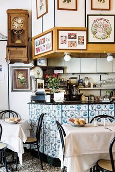 a restaurant with tables, chairs and pictures on the wall over the bar area that is decorated in blue and white tiles