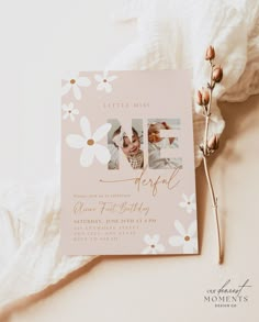 a pink and white photo birth announcement with daisies on the side, next to a baby's first birthday card