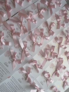 many pink bows are on top of white envelopes