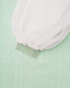 a piece of white fabric with a comb on it's end sitting on a green surface