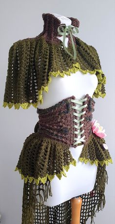 a white mannequin with green and brown crocheted shawl on top