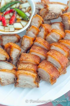 sliced pork and vegetables on a plate with dipping sauce