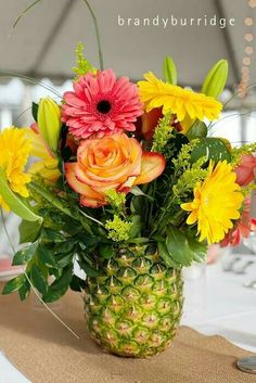 a pineapple vase filled with colorful flowers on top of a table