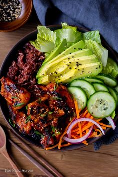 a bowl filled with meat and vegetables on top of a wooden table next to chopsticks