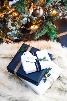 two presents wrapped in blue and white are sitting on a fur rug near a christmas tree