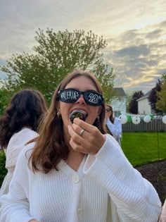 a woman wearing blindfolds and eating food in front of her eyes with other people behind her