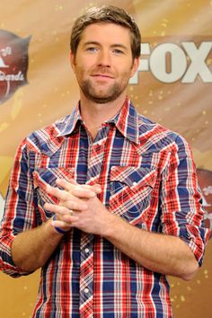 a man standing in front of a red and blue background with his hands folded up