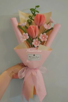 a hand holding a bouquet of pink flowers