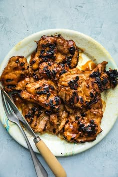 grilled chicken on a plate next to a fork and knife