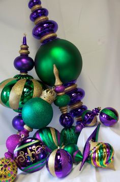 green and purple ornaments are arranged on a white surface with gold trimmings around them