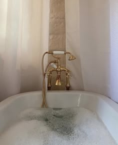 a white bath tub sitting under a window next to a shower head and hand held faucet