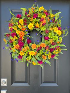 a colorful wreath on the front door of a house with blue doors and green trim