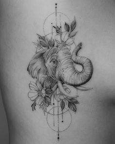 an elephant and flower tattoo on the back of a woman's stomach is shown