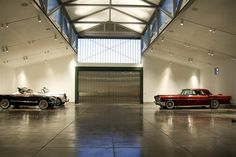 two classic cars are parked in an empty garage