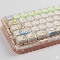 a clear plastic case holds a white and green keyboard with cartoon characters on it's keys