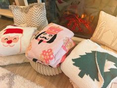 three christmas themed pillows sitting next to each other on a wooden floor in front of a fireplace