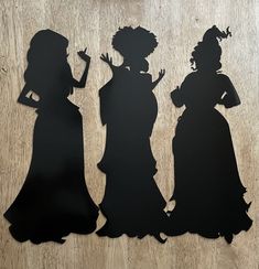 the silhouettes of three women in dresses are shown on a wooden surface, with one woman holding a cell phone