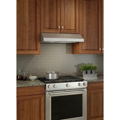 a stove top oven sitting inside of a kitchen next to wooden cabinets and counter tops