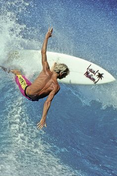 a man riding a surfboard on top of a wave in the ocean with his arms up