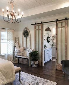 a bedroom with white walls, wooden floors and a chandelier hanging from the ceiling