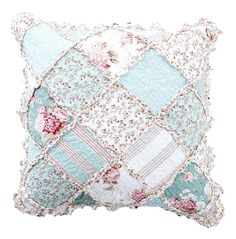 a blue and pink patchwork pillow with flowers on the front, sitting on a white surface