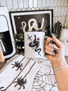 a woman holding a coffee mug in front of her artwork on the wall behind her