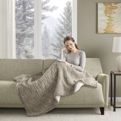 a woman sitting on a couch under a blanket