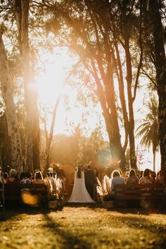 the bride and groom are getting married in front of an outdoor wedding ceremony with sun shining through the trees