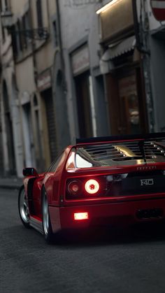 a red sports car parked on the side of a street next to tall buildings in an alleyway