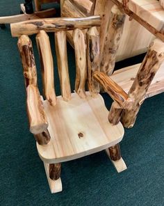 a wooden chair made out of logs sitting on the floor in front of a green carpet