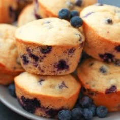 blueberry muffins piled on top of each other in a bowl with fresh blueberries