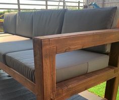 a wooden couch sitting on top of a wooden floor next to a green grass covered field