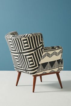 a black and white patterned chair sitting on top of a white floor next to a blue wall