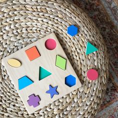 a wooden puzzle sitting on top of a wicker basket next to a woven rug