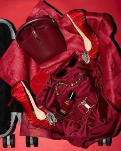 the contents of a woman's purse and shoes are laid out on a pink surface